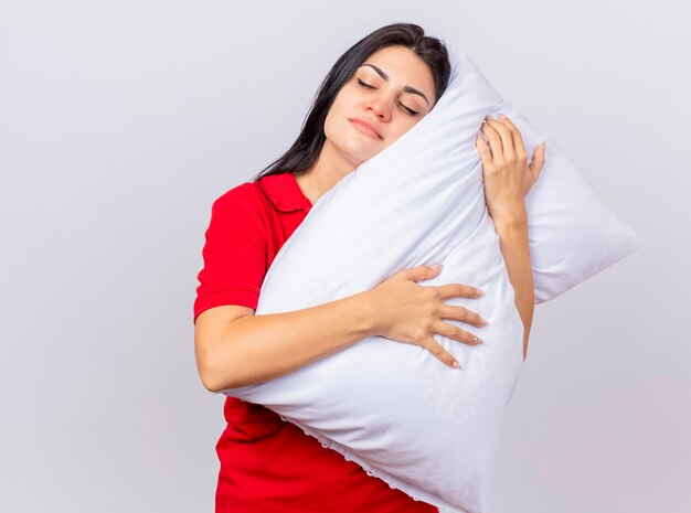 Sleepy young caucasian ill girl hugging pillow putting head on it with closed eyes isolated on white background with copy space