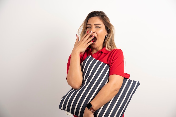 Free Photo sleepy young woman hugging her pillow on whiten background.