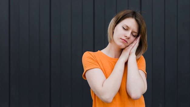 Sleepy young woman standing against black backdrop