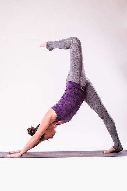 Slender young woman doing yoga exercise. Isolated over white background.