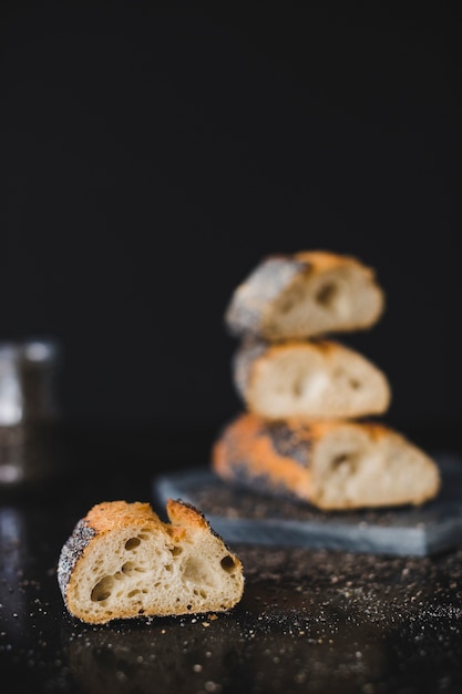Slice of baked bread with chia seeds on black background
