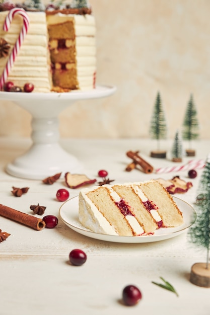 Slice of biscuit with layers of cream on a plate and a cake behind