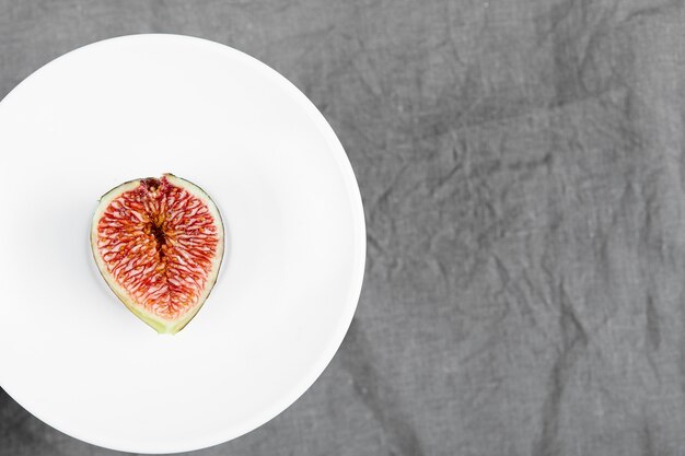 A slice of black fig on a white plate. High quality photo