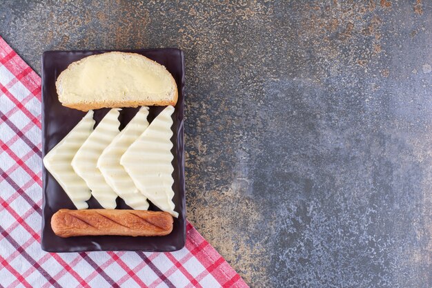 A slice of bread served with sausages and cheese on a wooden board