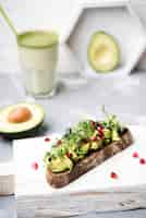 Free photo slice of bread with avocado pasta and glass of smoothie