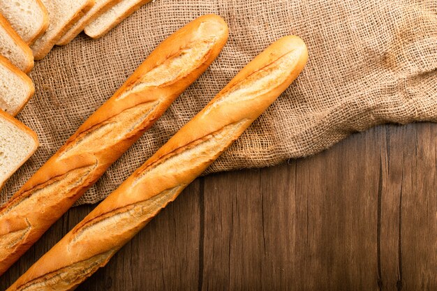 Slice of bread with baguette on tablecloth