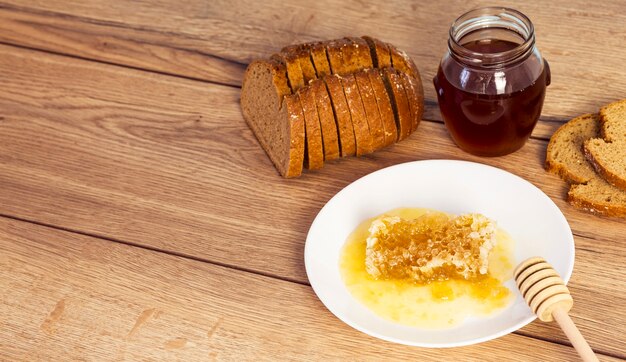 Slice of bread with honey and honeycomb on wooden texture backdrop