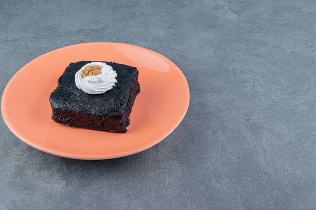 Slice of brownie cake on orange plate.