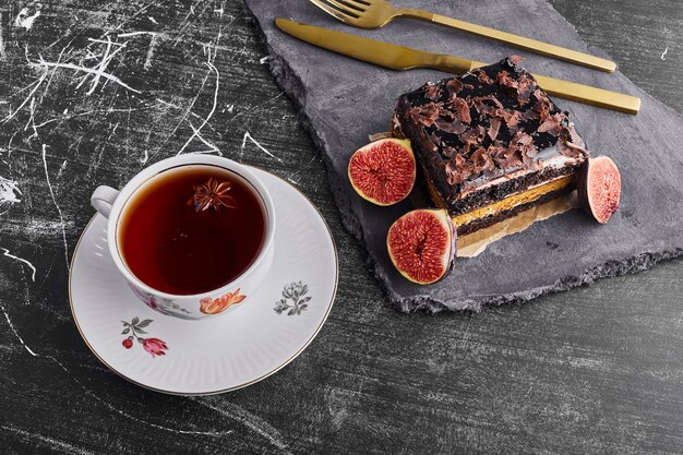 A slice of brownie cake with figs and a cup of tea. 
