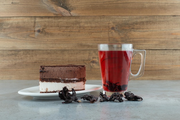 Slice of cake and glass of tea on marble table.