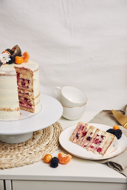 白い背景の後ろのテーブルにベリーとパッションフルーツとケーキのスライス