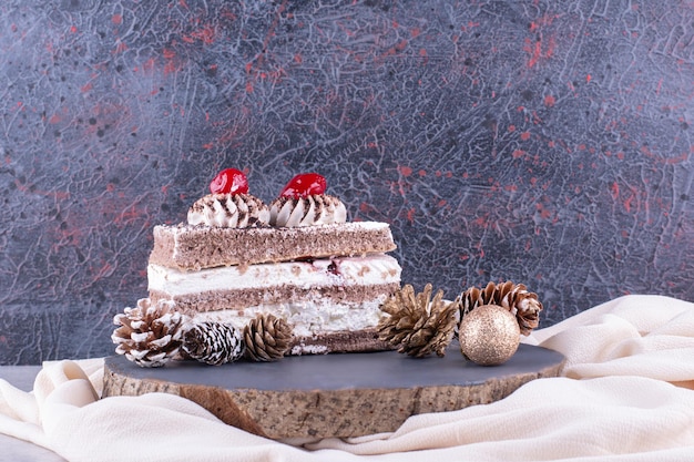 木片にクリスマスの飾りが付いたケーキのスライス。高品質の写真