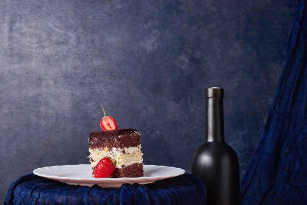 A slice of cake with cocoa and strawberries in a white plate. 