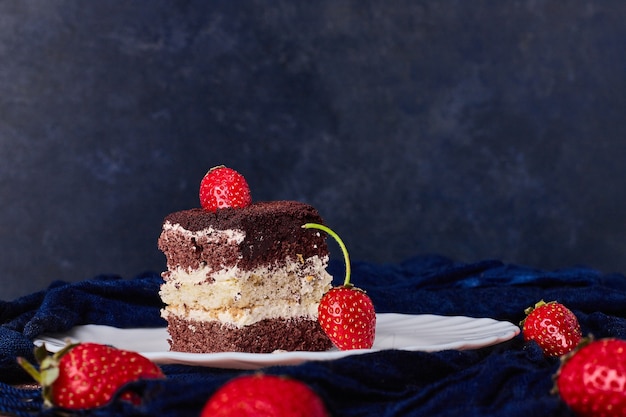 A slice of cake with cocoa and strawberries. 