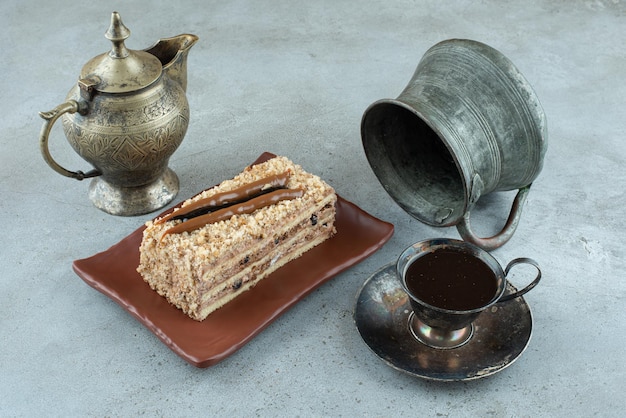 Fetta di torta con una tazza di tè e una tazza da tè sulla superficie di marmo.