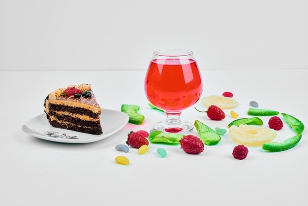 A slice of cake with fruits and drink.