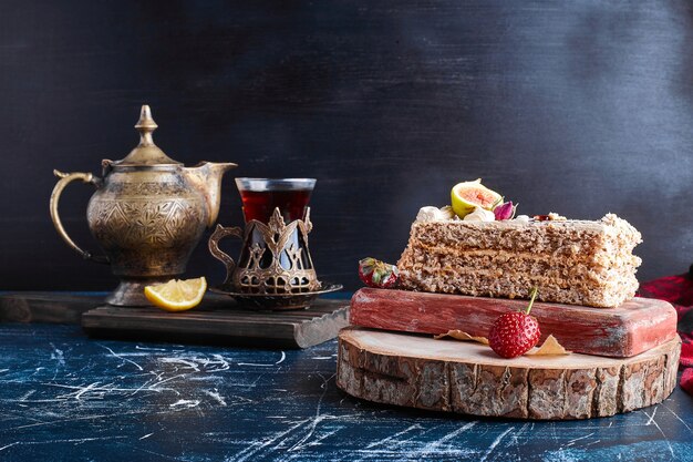 A slice of cake with a glass of tea on blue surface. 