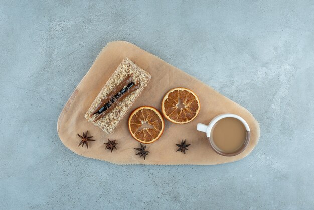 Slice of cake with orange slices and coffee on wooden board. High quality photo
