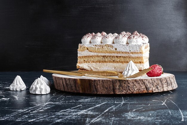 A slice of cake on a wooden board. 