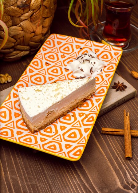 Slice of caramel vanilla cheesecake on plate against a rustic brown wood table