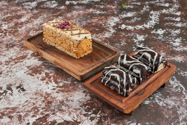 Slice of carrot cake with brownies on a wooden board.