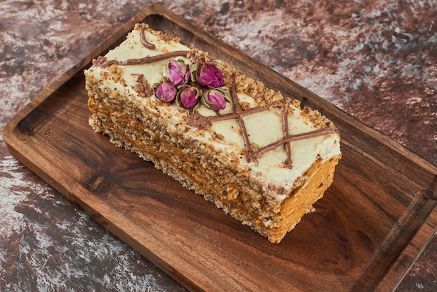 Slice of carrot cake on a wooden board.