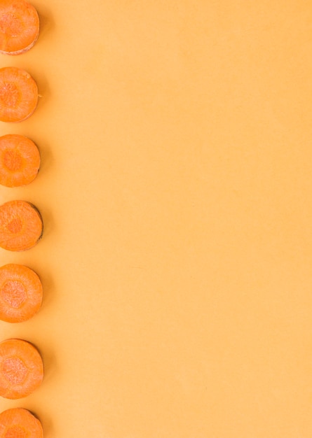 Free photo slice of carrots in a row on orange background