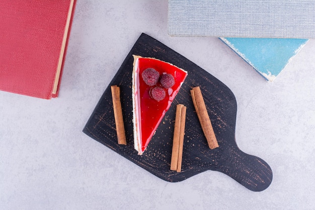 Slice of cheesecake with cinnamon sticks on dark plate. High quality photo