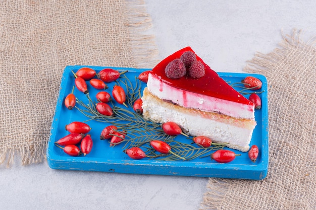 Slice of cheesecake with fresh rosehips on blue plate.