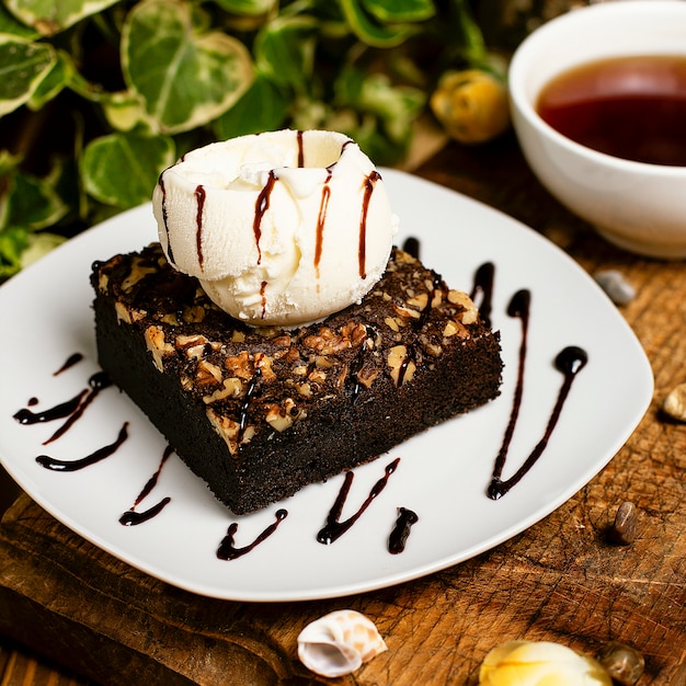 A slice of chocolate brownie with walnut and vanilla ice cream.