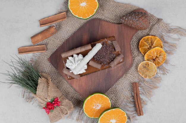 Slice of chocolate cake, cinnamon and slices of tangerine on burlap. High quality photo