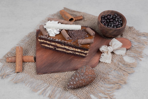 Slice of chocolate cake, cinnamons and pinecone on burlap. High quality photo