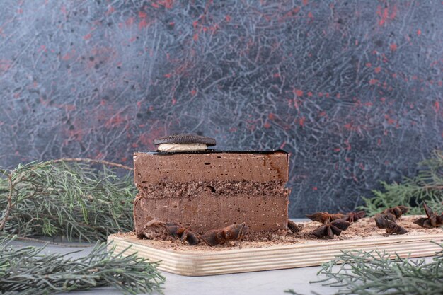 Slice of chocolate cake with cloves on wooden board. High quality photo