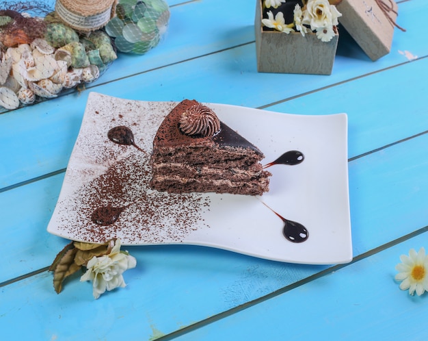 A slice of chocolate cake with cocoa powder.