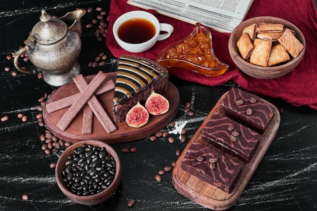 Slice of chocolate cake with cookies and tea.