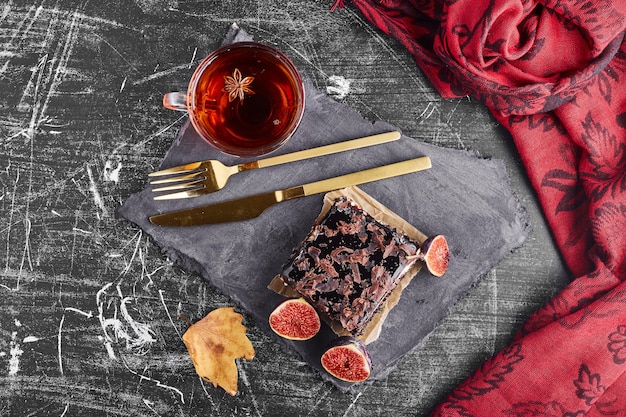 A slice of chocolate cake with a cup of tea, top view. 