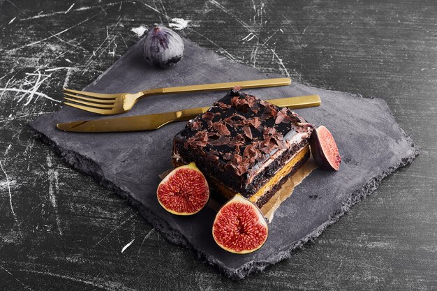 A slice of chocolate cake with figs on a stone platter. 