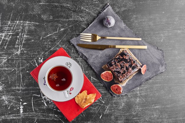 A slice of chocolate cake with figs and tea, top view. 