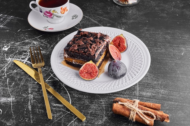 무화과와 하얀 접시에 차 초콜릿 케이크 한 조각.