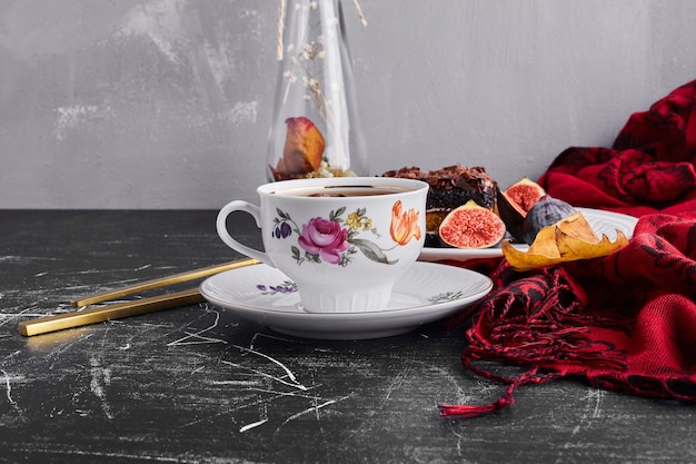 A slice of chocolate cake with figs and tea. 