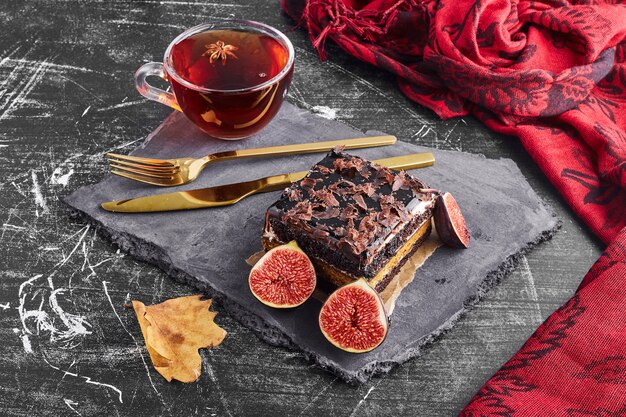 A slice of chocolate cake with fruits and a cup of tea.