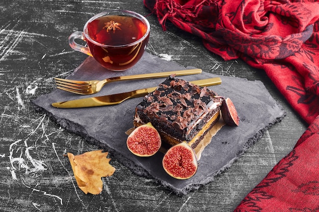 A slice of chocolate cake with fruits and a cup of tea. 