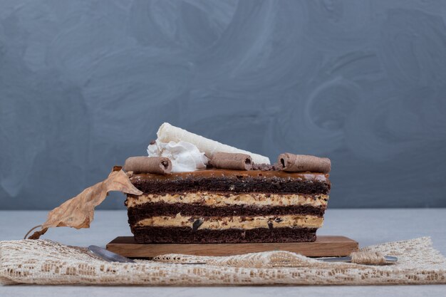 Slice of chocolate cake with leaf on marble table. High quality photo