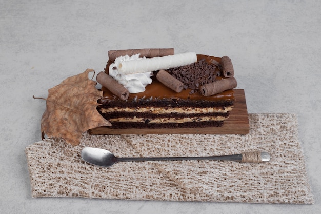 Foto gratuita fetta di torta al cioccolato con foglia e cucchiaio sul tavolo di marmo. foto di alta qualità