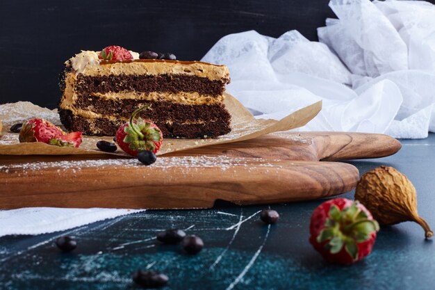 A slice of chocolate cake on a wooden board. 