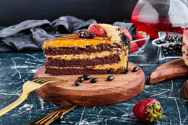 A slice of chocolate cake on a wooden board. 