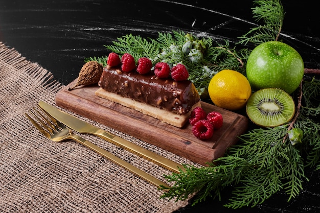 Slice of chocolate cake on wooden platter.