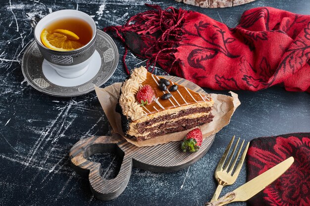 A slice of chocolate caramel cake with a cup of tea. 