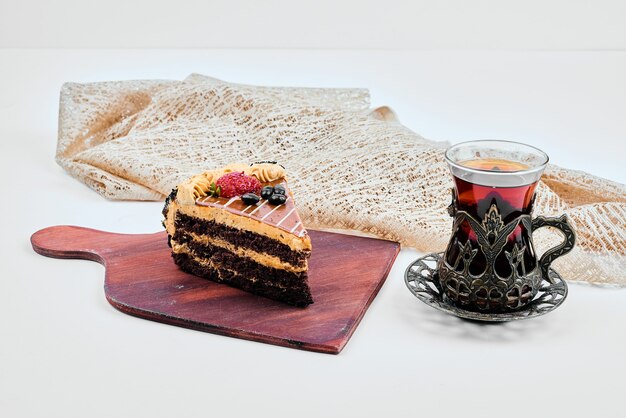 A slice of chocolate caramel cake with a glass of tea.