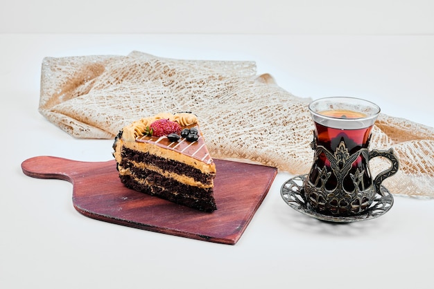 A slice of chocolate caramel cake with a glass of tea.